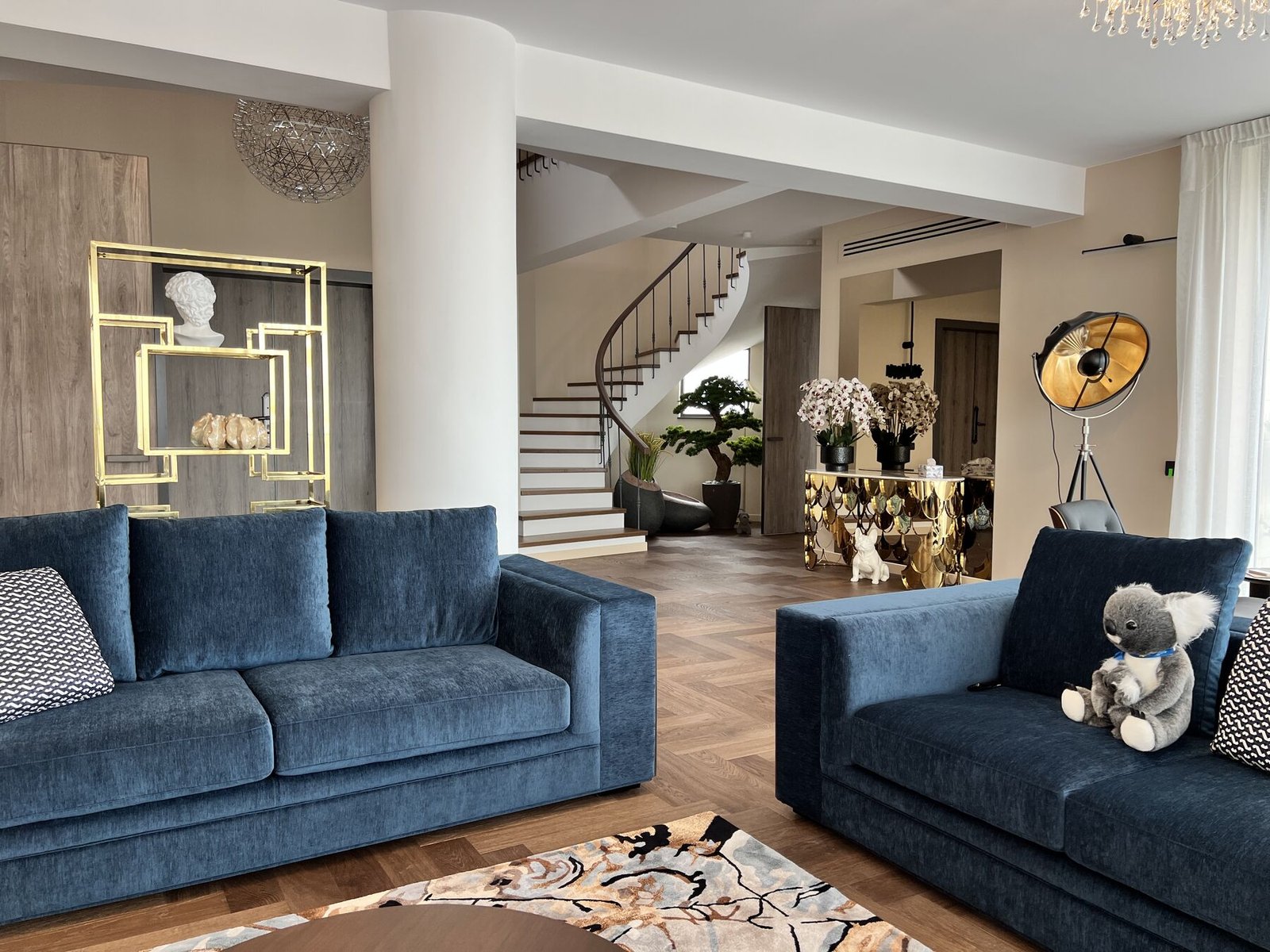 Living room with deep blue sofa and floating staircase