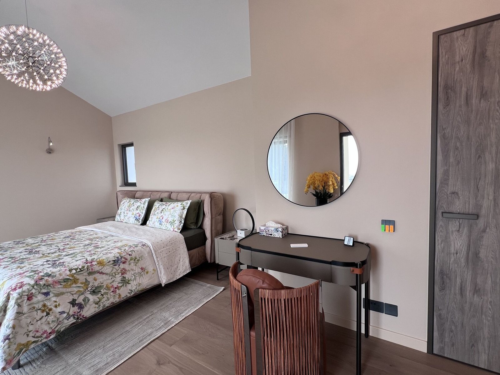 Master bedroom with round mirror and warm tones